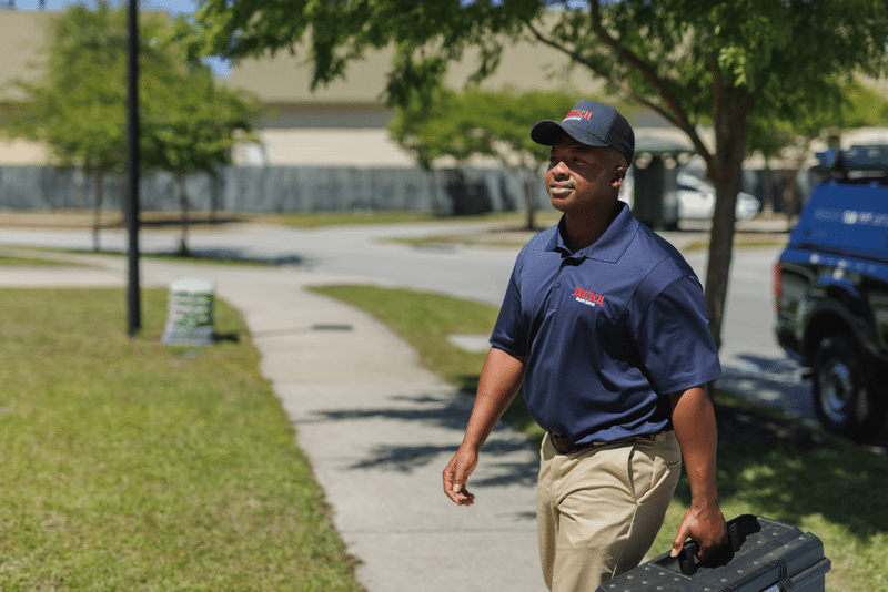 Trutech repair technician with tool box approaching house